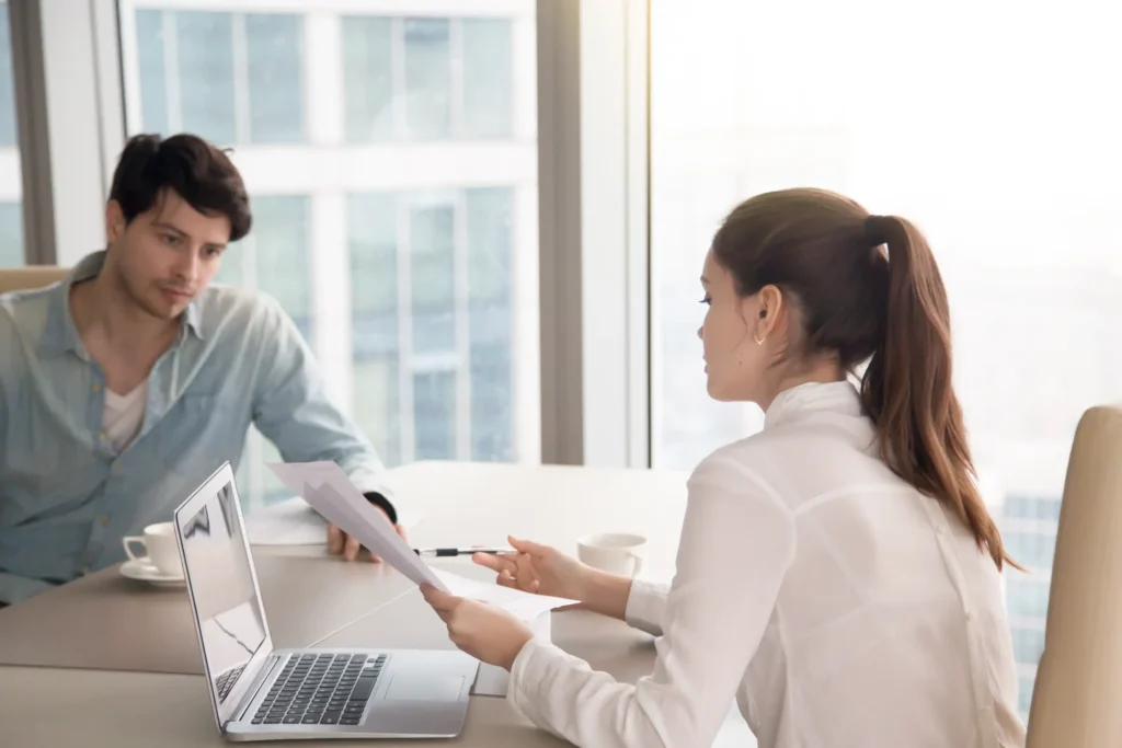 "Professional business meeting between colleagues discussing project documents in modern office setting"