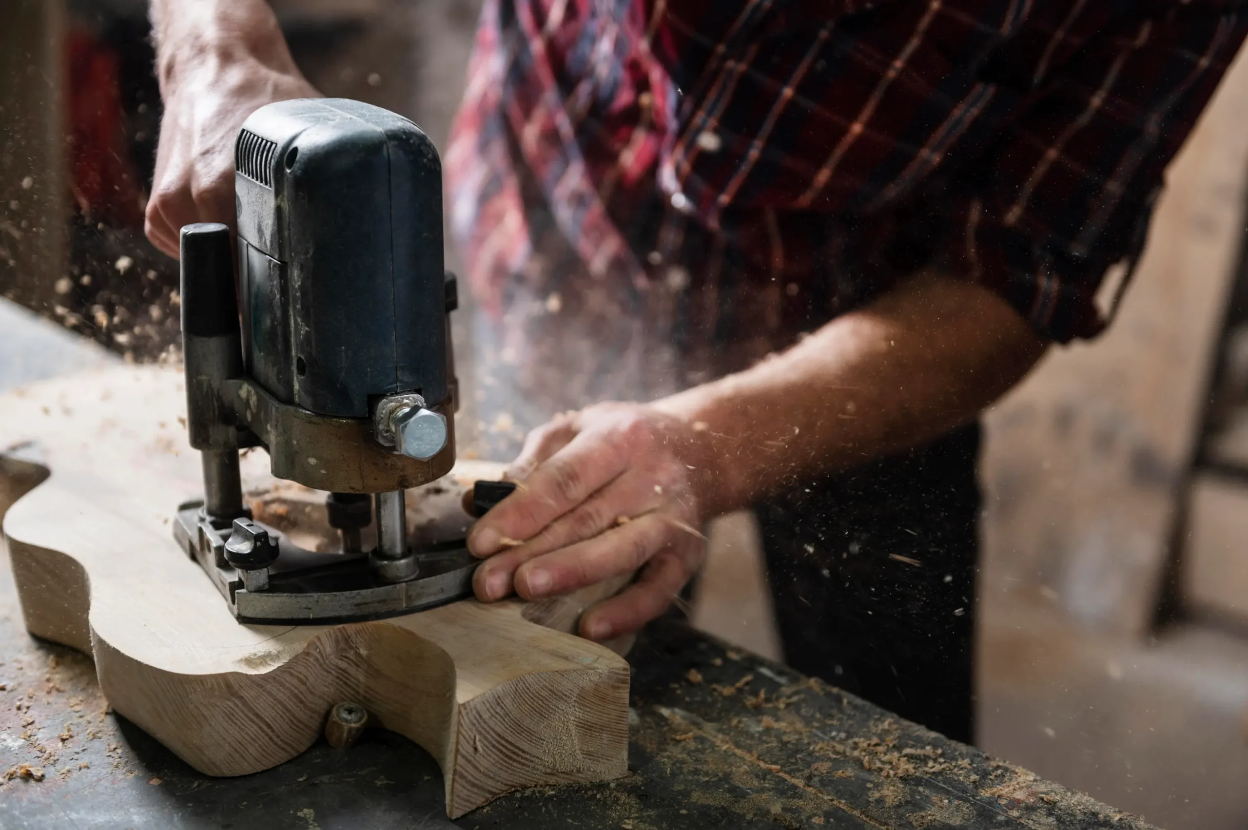 "Woodworker using router tool on wooden piece in workshop"