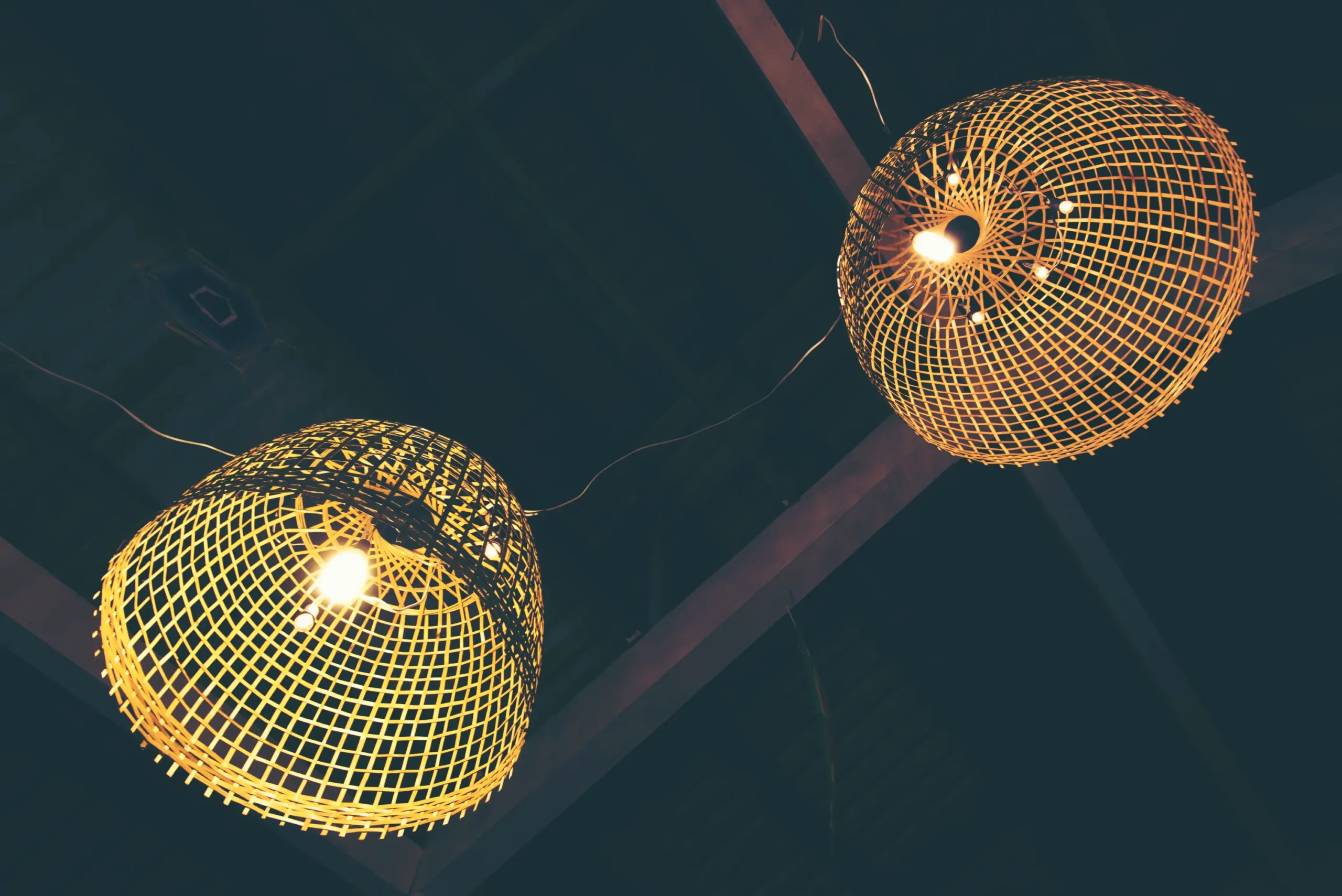 "Woven bamboo pendant lights with geometric lattice pattern hanging from dark ceiling"