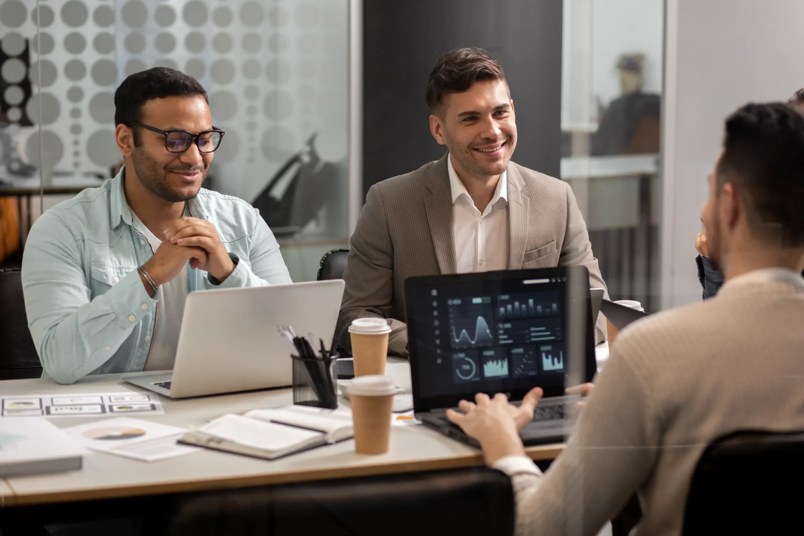 "Business professionals analyzing data analytics during team meeting with laptops and digital dashboards"