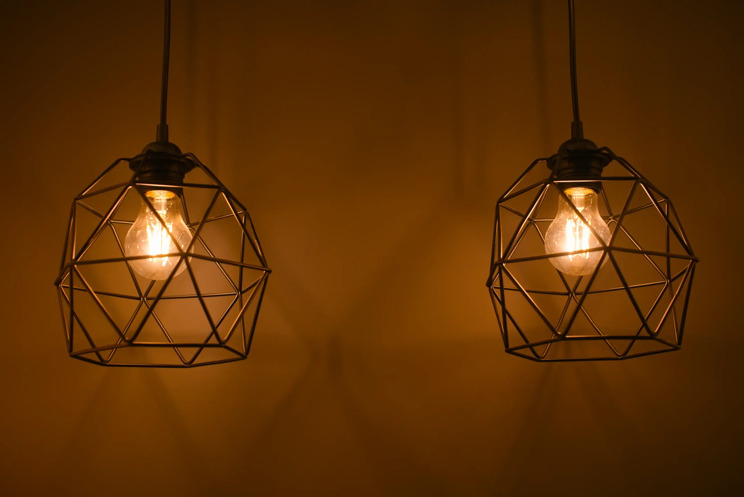 "Geometric pendant lights with Edison bulbs in industrial-style cages"