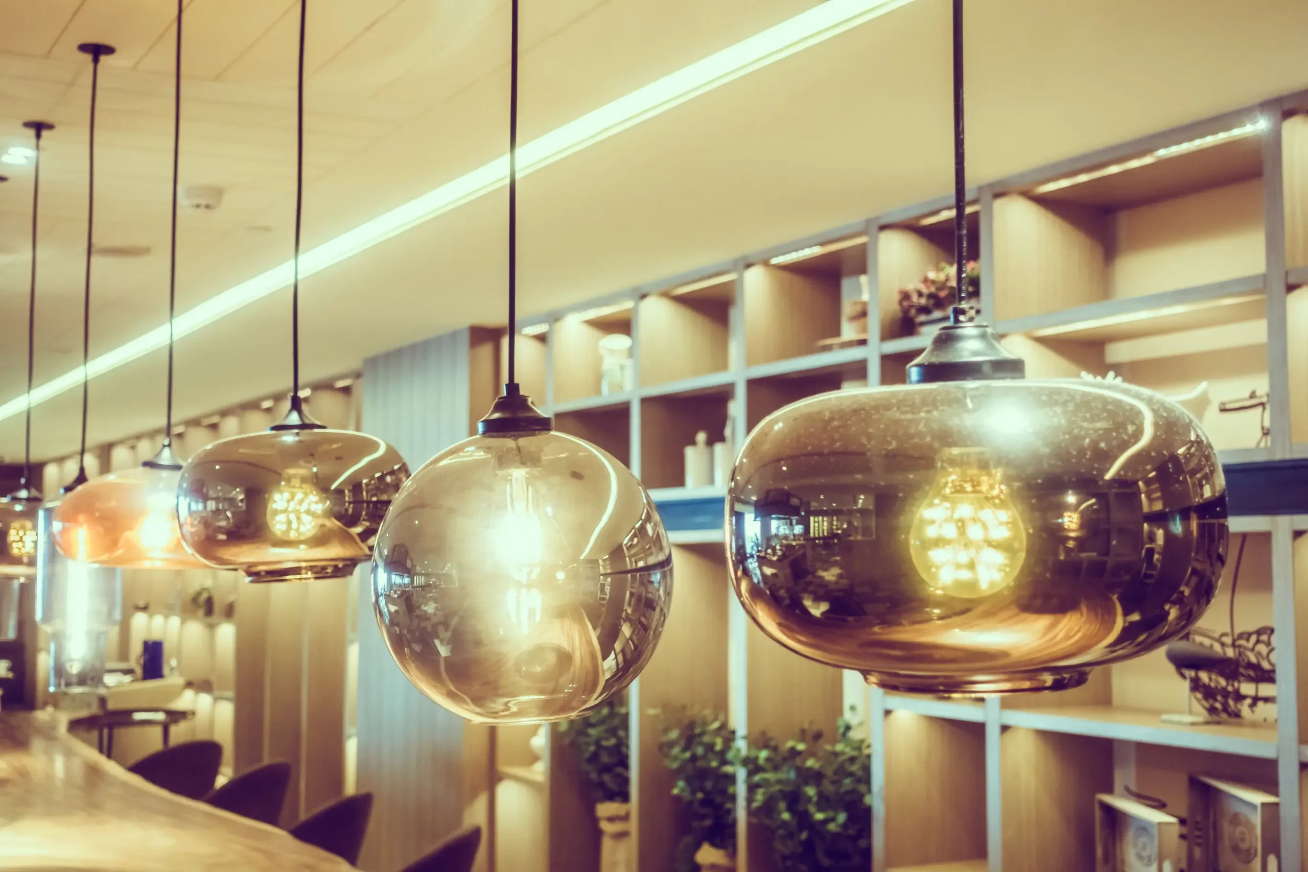 "Modern glass pendant lights with spherical shades in warm ambient restaurant interior"