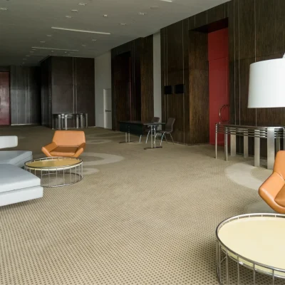 "Modern hotel lobby interior with tan leather armchairs, white curved sofa, and contemporary round coffee tables"